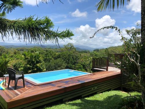 a pool with a deck and a chair next to it at daintree valley cottage in Daintree