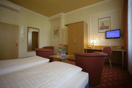 a hotel room with two beds and a desk and a television at Hotel Königshof in Mainz