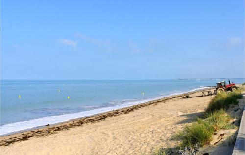 a tractor on a sandy beach near the ocean at Nice Home In Auxais With Wifi in Auxais