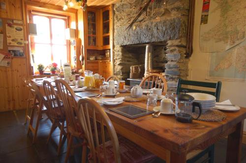 a wooden table with chairs and a stone fireplace at Bryn Elltyd Eco House in Blaenau-Ffestiniog