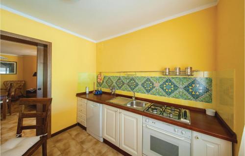 eine gelbe Küche mit einer Spüle und einem Herd in der Unterkunft Le Dune in Sorso