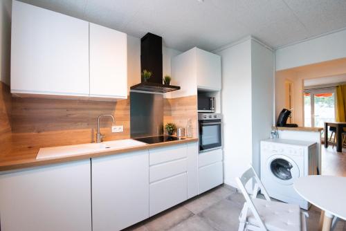 cocina con armarios blancos, lavadora y secadora en Appartement du Vercors - 3 Bedrooms Parking Free Netflix en Fontaine