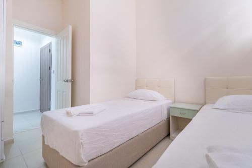 two beds in a white room with a window at Apartments Near to City Center and Beach in Marmaris