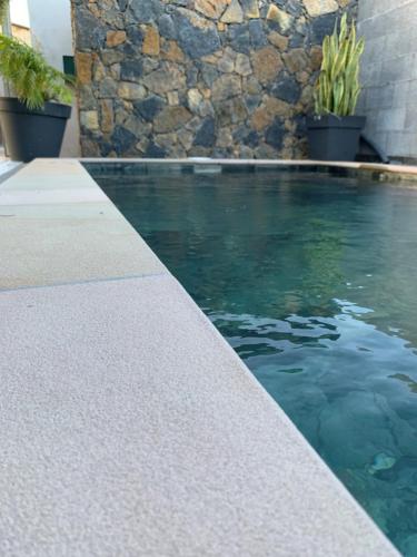 a swimming pool next to a stone wall at Ti Kaz Fantaisie in Le Patelin