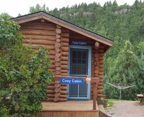 a log cabin with a blue door and a sign at River Falls Lodging -Black Hills, South Dakota in Hot Springs