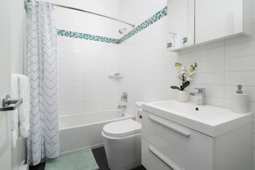een witte badkamer met een bad, een toilet en een wastafel bij Hotel-Apart Prince Arthur in Montreal