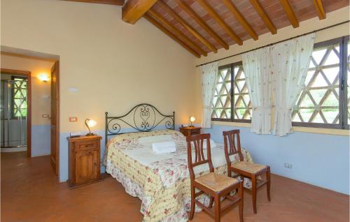 a bedroom with a bed with two chairs and two windows at La Casetta in Montepulciano