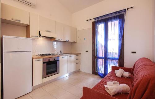 uma cozinha com electrodomésticos brancos e um sofá vermelho em Nice Apartment In Costa Rei -ca- With Kitchenette em Monte Nai
