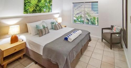 1 dormitorio con 1 cama con silla y ventana en REEF RETREAT APARTMENTS PALM COVE Unit 13, en Palm Cove