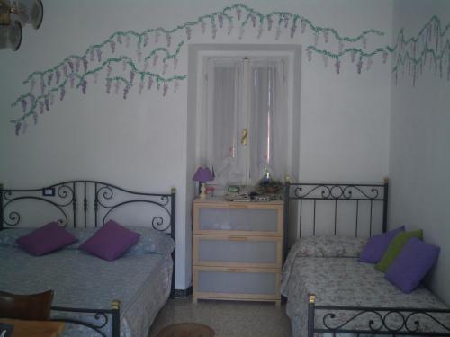 a bedroom with two beds and a dresser with purple pillows at B&B Balestruccio in Pombia