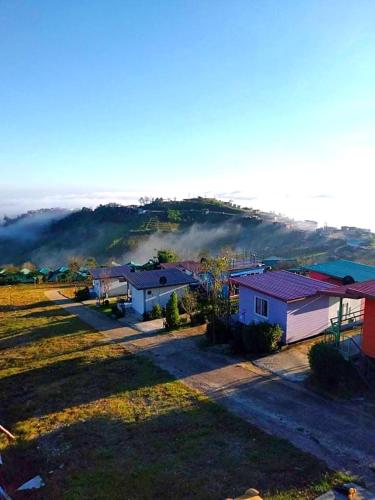 a group of houses in a field with a hill in the background at ไร่รุ่งอรุณ ภูทับเบิก in Ban Maeo Thap Boek