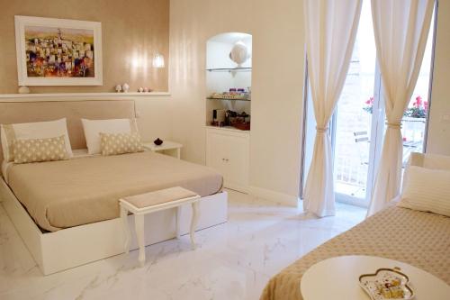 a white bedroom with two beds and a window at Porta Piccola Luxury Home in Bari