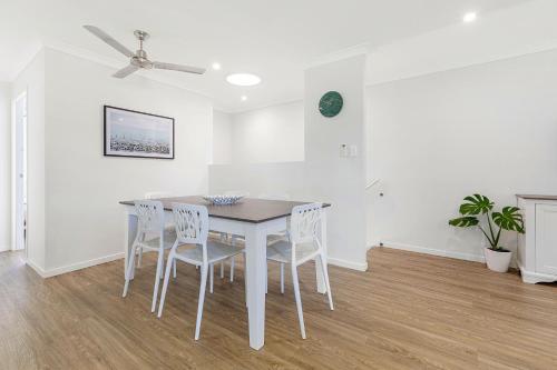 - une salle à manger blanche avec une table et des chaises blanches dans l'établissement 3BR, 3BTH, Walk to Beach & City Centre, à Maroochydore
