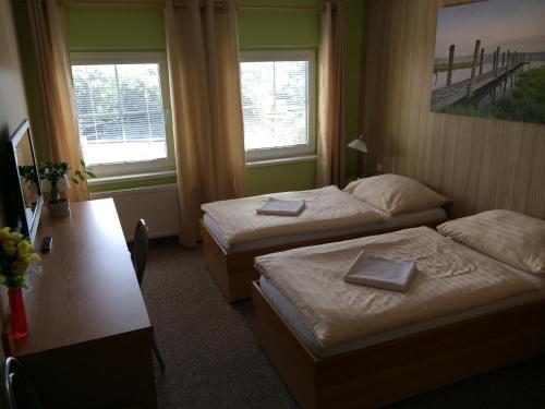 a hotel room with two beds and a desk and two windows at Hotel Pohádka in Most