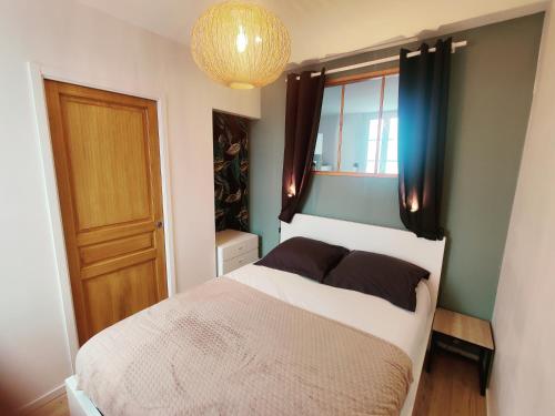 a bedroom with a bed and a window and a chandelier at F2 - 30m2 Face à la mer in Luc-sur-Mer