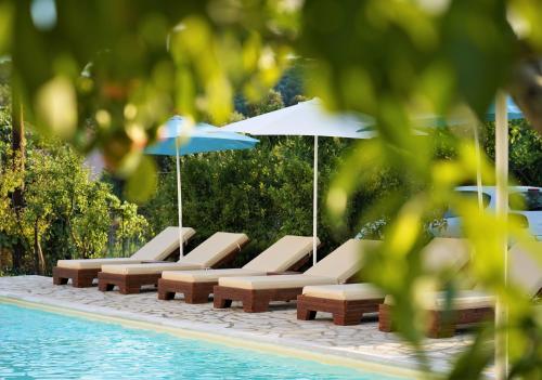 a row of lounge chairs and umbrellas next to a pool at Villa Apollo in Parga