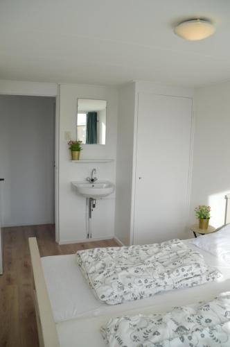Habitación blanca con cama y lavabo en Seapaerdje, en Bergen aan Zee