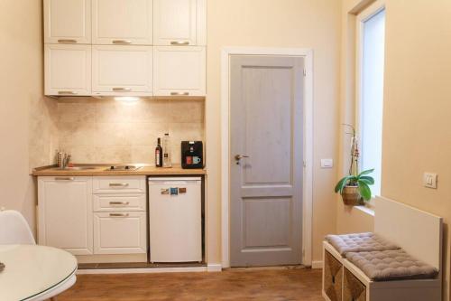 a kitchen with white cabinets and a white refrigerator at Charming Apartment in Historical City Center in Timişoara