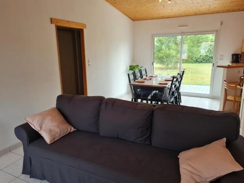 a living room with a couch and a table with chairs at Maison des Trèmières in Brem-Sur-Mer