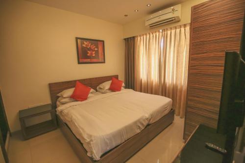a bedroom with a bed with red pillows and a window at The Gold Haven in Pune