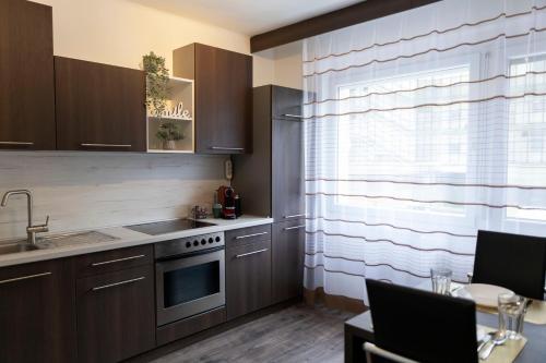 a kitchen with brown cabinets and a sink and a window at Komló Szíve Apartman in Komló