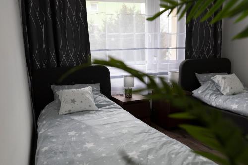 a bedroom with two beds and a window at Komló Szíve Apartman in Komló