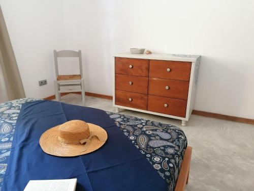 a straw hat sitting on a bed with a dresser at Villa Pescadora spectacular view, luxery fisherhouse design in Sal Rei