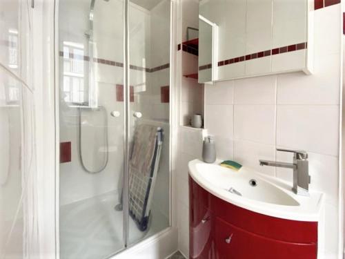La salle de bains est pourvue d'un lavabo rouge et d'une douche. dans l'établissement Appartement coquet sur les hauteurs de Montmartre, à Paris