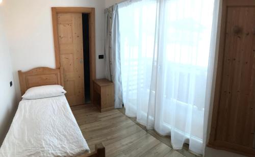 a bedroom with a bed and a large window at Garnì Aurora Bed and Breakfast in Soraga