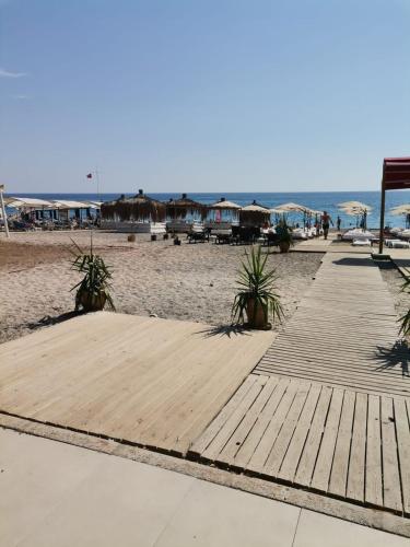 a wooden path on the beach with houses in the background at Kiriş Garden Hotel in Kemer