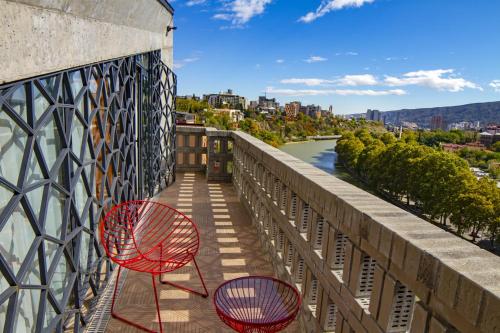 two red chairs on a balcony overlooking a river at Sandali Metekhi Boutique Hotel in Tbilisi City