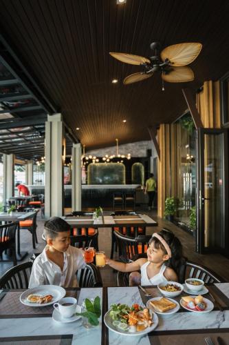 twee kinderen aan een tafel met borden eten bij Ananta Burin Resort in Ao Nang Beach