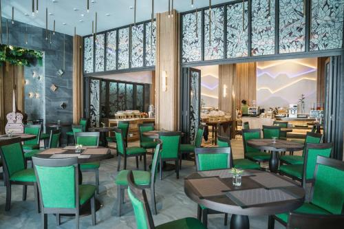 een restaurant met houten tafels en groene stoelen bij Ananta Burin Resort in Ao Nang Beach