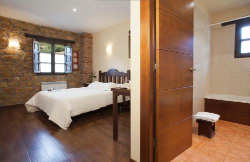 a bedroom with a bed and a bathroom with a tub at Hotel Rural El Fundil in El Pino