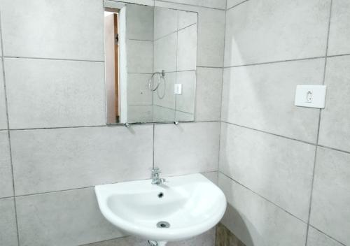 Baño blanco con lavabo y espejo en Pousada Maceio, en Maceió