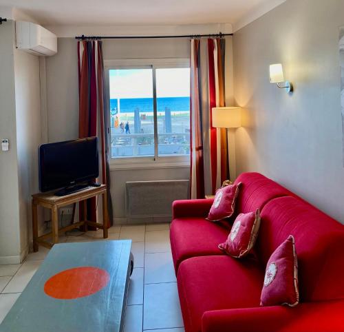 uma sala de estar com um sofá vermelho e uma televisão em Appartement Front de Mer em Canet-en-Roussillon