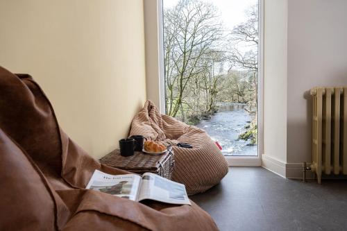 a living room with a couch and a window at Mint Mill: New riverside apartment in historic mill in Kendal