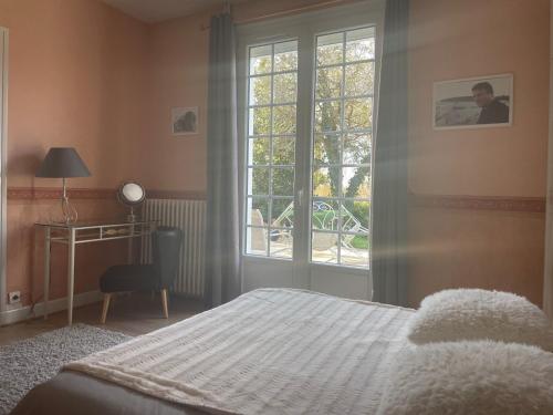1 dormitorio con cama, ventana y escritorio en Un petit coin de paradis, en Bressolles