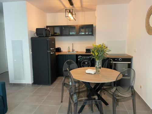 une cuisine avec une table avec des chaises et un réfrigérateur dans l'établissement Bel Appartement au calme avec parking, à Menton