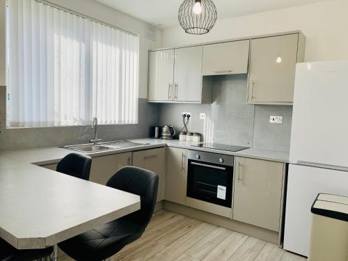 uma cozinha com armários brancos e uma mesa e cadeiras em Stunning 3 bed residential home in Sheffield em Sheffield