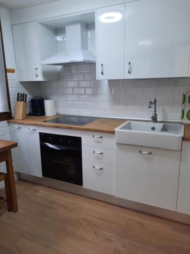 una cocina con armarios blancos y fregadero en Casa de la Parra, en Mogarraz