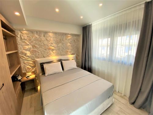 a bedroom with a bed and a stone wall at Kali Thea Suites in Neos Marmaras