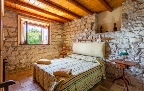 a bedroom with a bed and a stone wall at Cozy Home In Ragusa With Kitchen in Camemi