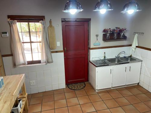 a kitchen with a red door and a sink at Aan de Bergen in Swellendam
