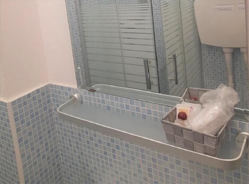 a bathroom with a mirror and a blue tiled wall at Hotel Enrica in Cervia