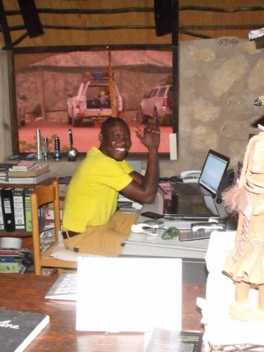 a man sitting at a desk in a room at Kapika Waterfall Lodge in Epupa