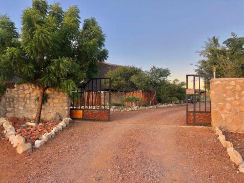a dirt road with a gate in front of a house at Kapika Waterfall Lodge in Epupa
