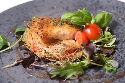 a plate of food with tomatoes and greens on it at Schwarzer Bär Jena in Jena