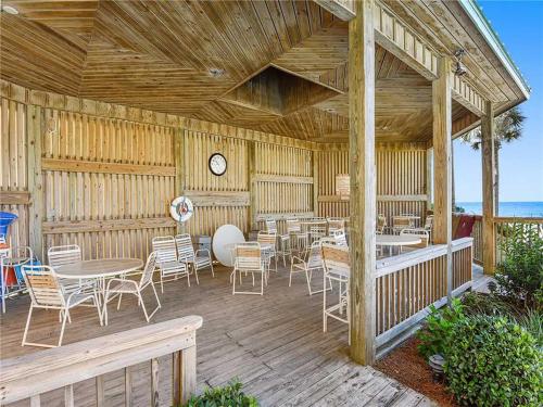a wooden deck with tables and chairs and a clock at Hidden Dunes 304 in Panama City Beach