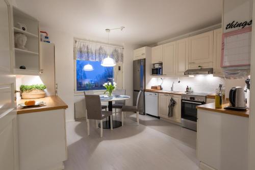 una cocina con armarios blancos y una mesa. en Modern design w/balcony, free parking,WiFi & A/C en Lappeenranta